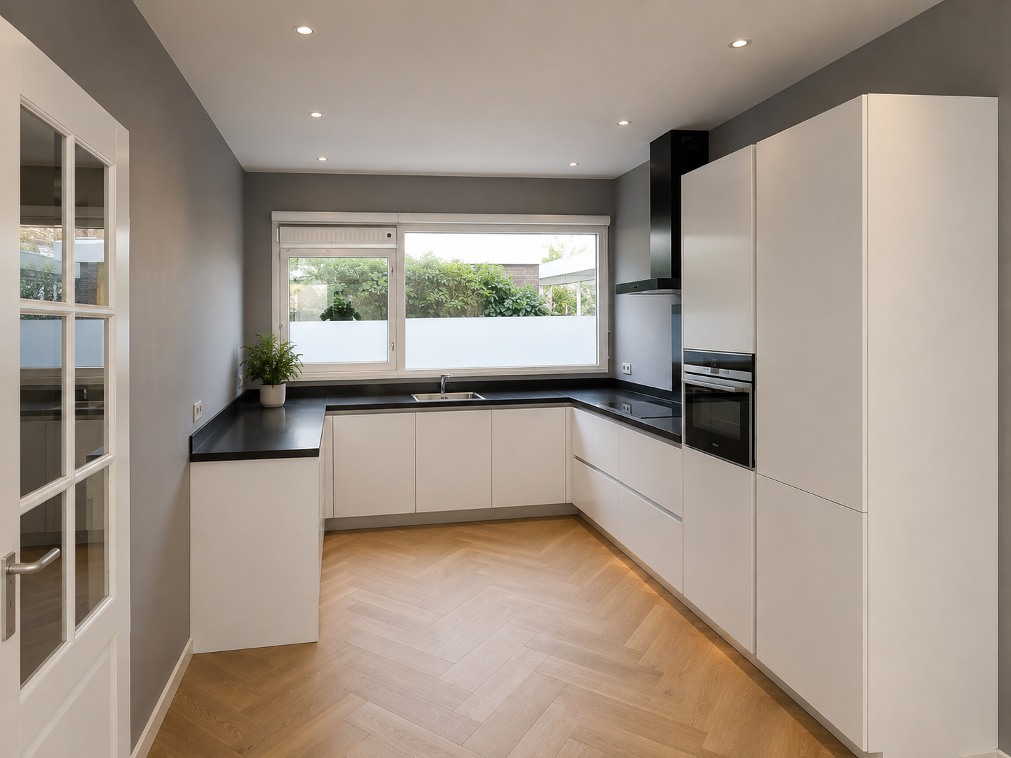 Strakke witte keuken met zwart werkblad en visgraatvloer in Zoetermeer